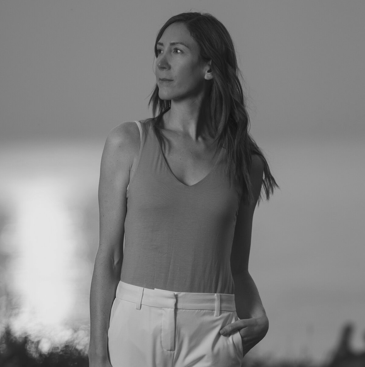 Relaxed woman standing by water during sunset, embodying calm and mindfulness, related to wellness a.