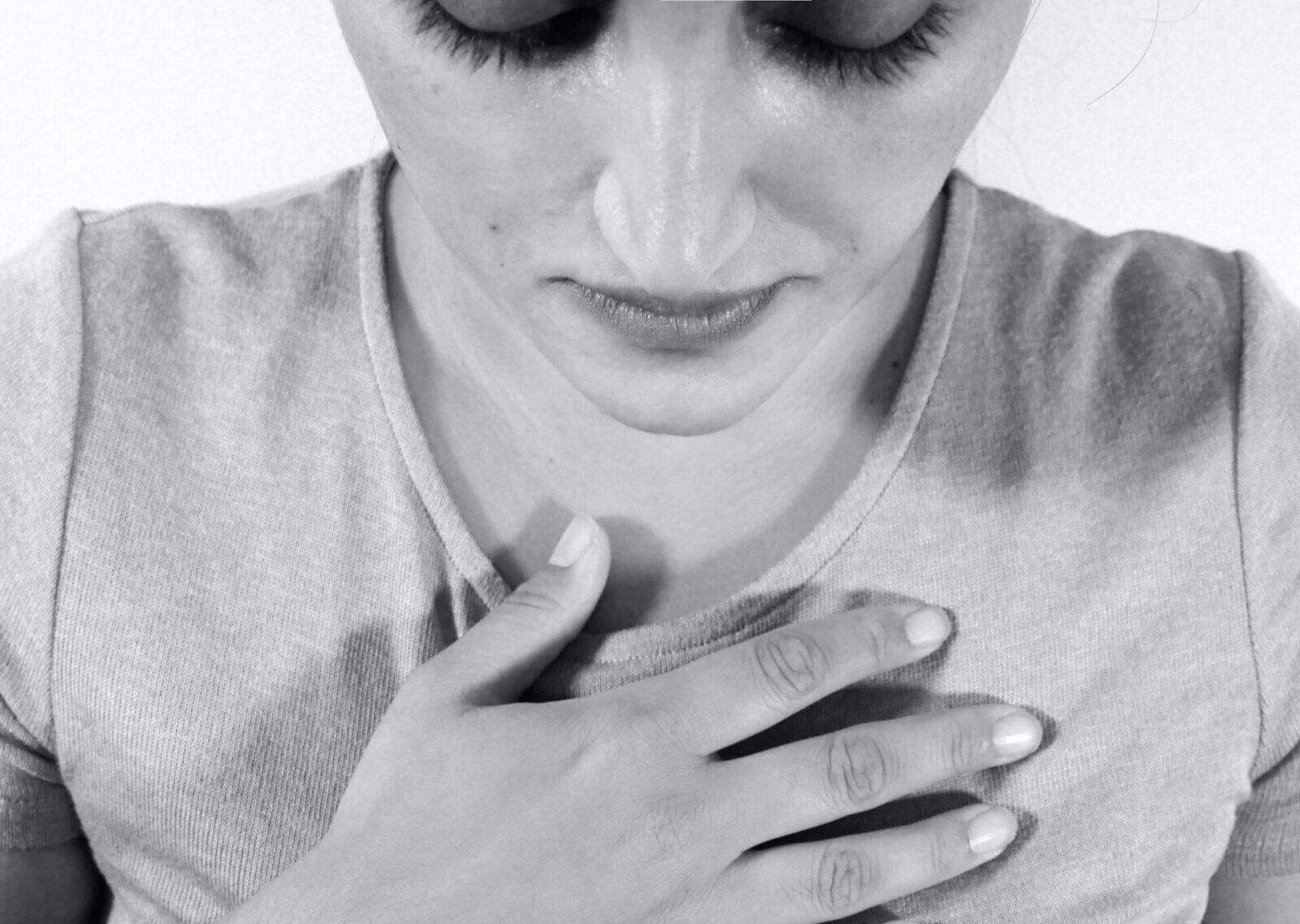 Black and white photo of a person holding their chest, symbolizing introspection and personal transformation.