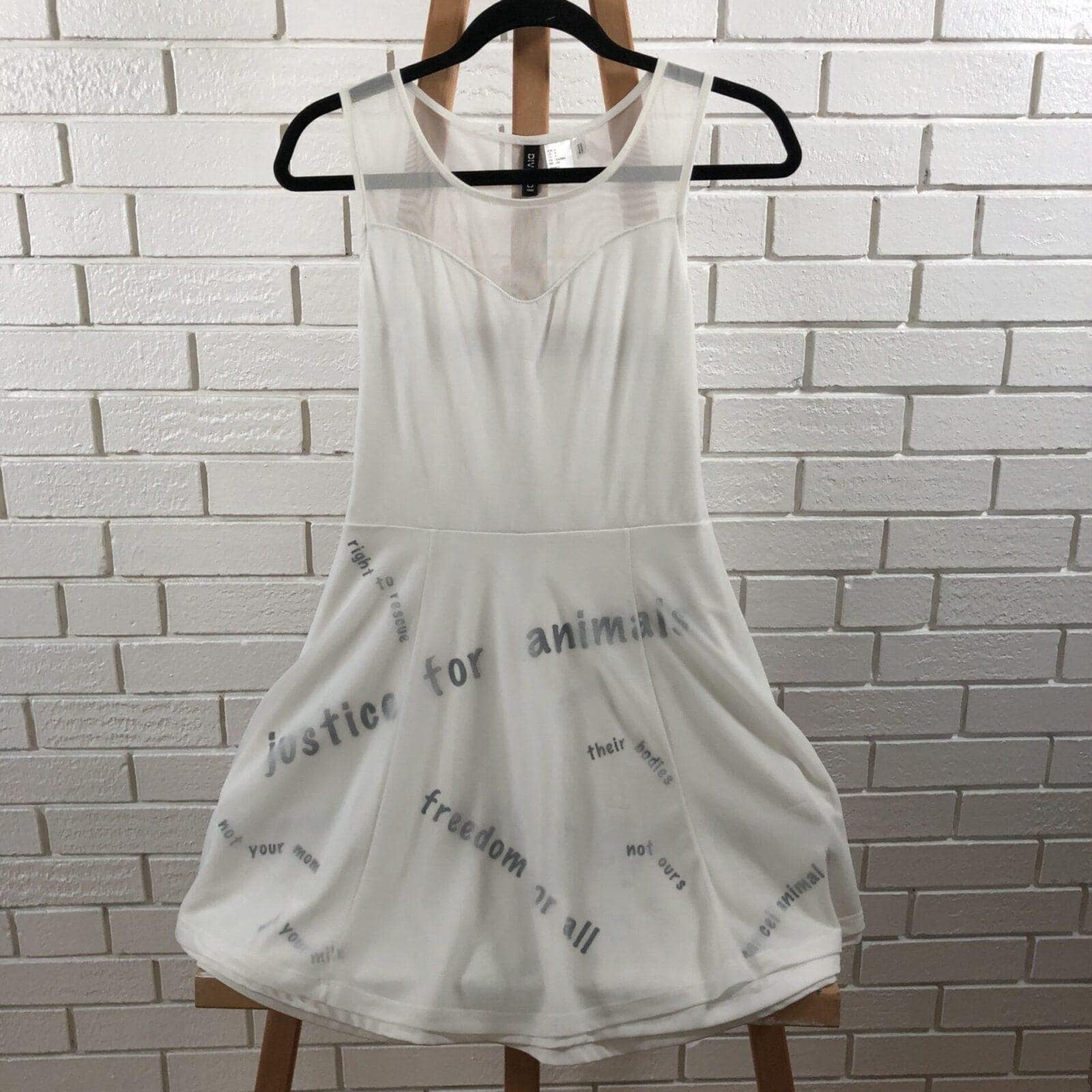 Close-up photo of a white dress with the phrases including "Justice for animals," "Freedom for all," and "Your milk is not for us" printed on it.
