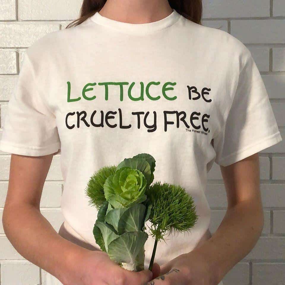 Laura wears a t-shirt from The Honest Whisper that playfully reads "LETTUCE be cruelty free" while holding up green plants below the text.