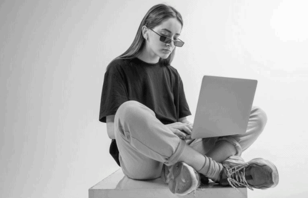A woman sitting while working on her laptop, representing a balanced and low-maintenance approach to online presence and blogging.