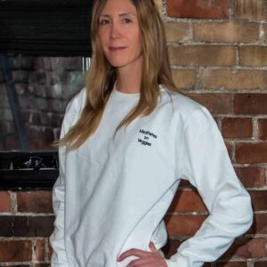 Woman wearing a white sweatshirt with the text "Meditates on Veggies" printed on the chest, promoting a vegan lifestyle.