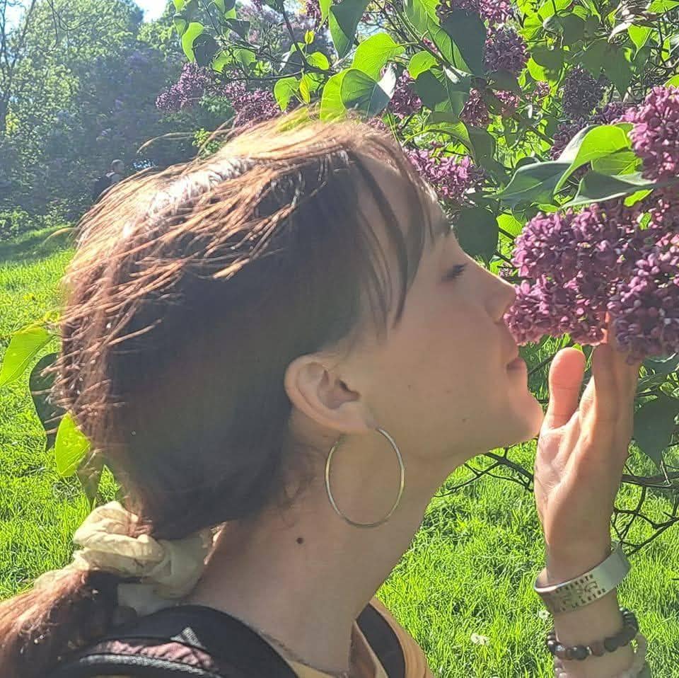 Woman enjoying the scent of lilacs in a lush garden setting.
