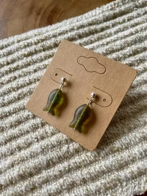Fish-shaped earrings with metallic finish on a cardboard display.